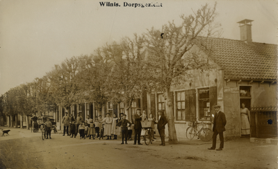 15304 Gezicht in de Dorpsstraat met bebouwing en leilinden te Wilnis uit het westen; met een grote groep personen. N.B. ...